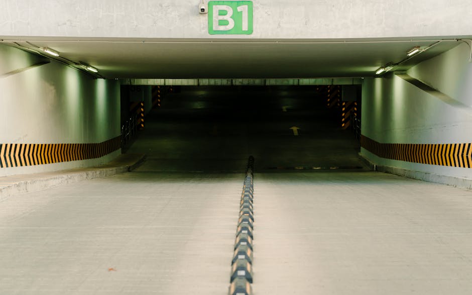 Close-up image of a row of stainless steel turnstiles with vertical bars and control panels, positioned inside a station area with a concrete floor. The turnstiles are designed for access control, fea